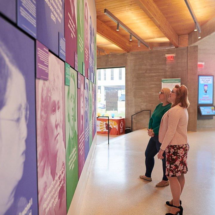 Interior of a building with two women looking at art on the walls